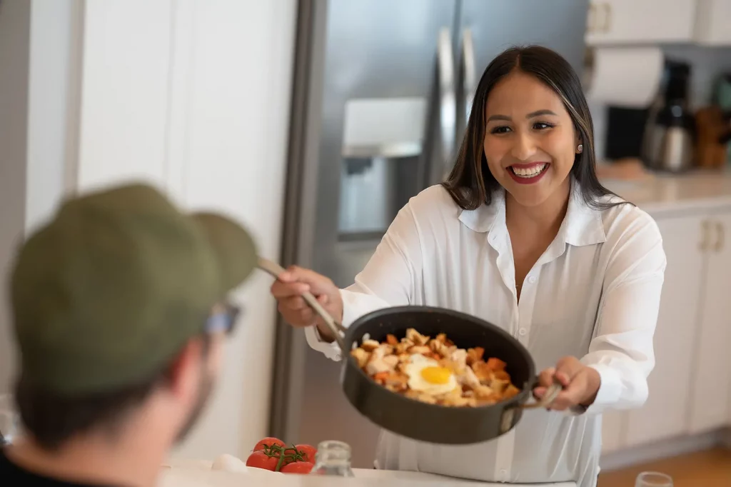 A smiling woman serving a meal to her friends